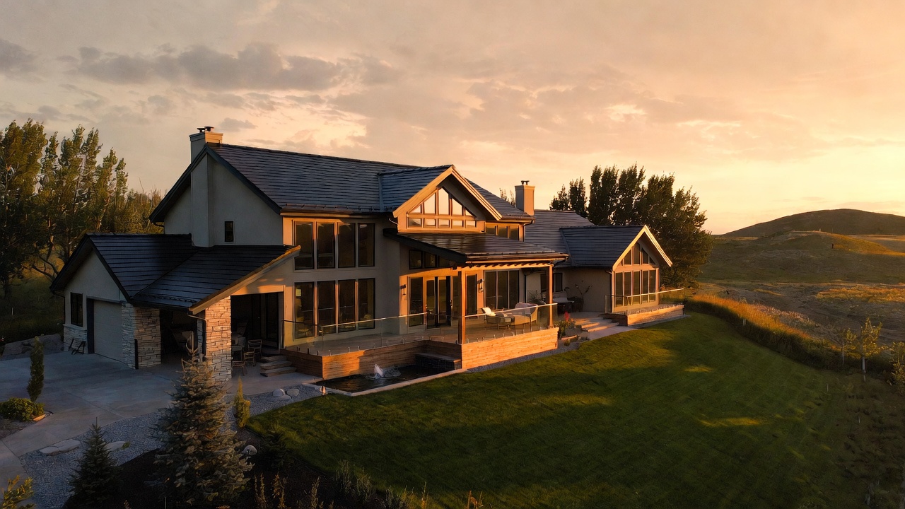 A modern custom home at golden hour, stone and dark roof set on prairie land